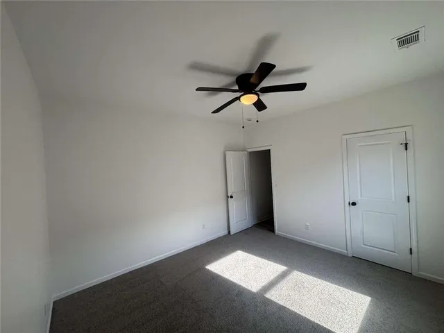 an empty room with a ceiling fan and carpet