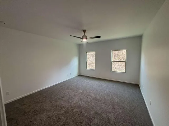 an empty room with windows and ceiling fan