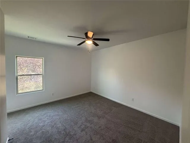 an empty room with chandelier fan and windows