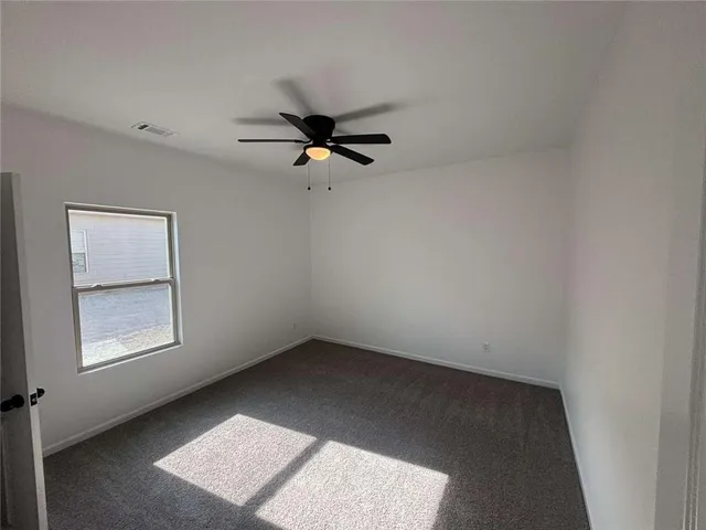 an empty room with a window and a ceiling fan