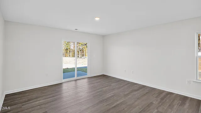 a view of an empty room with wooden floor and window