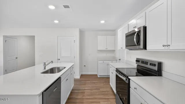 a kitchen with granite countertop a sink and a stove top oven with wooden floor