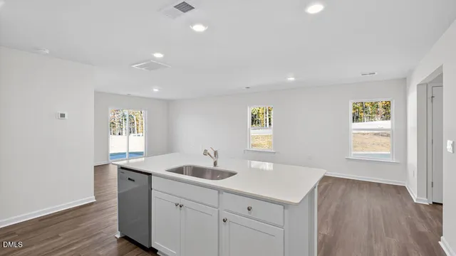 a kitchen with a sink cabinets wooden floor and a window