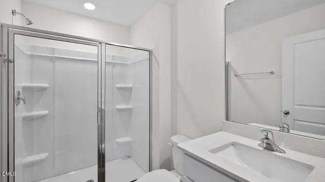 a bathroom with a shower sink vanity and toilet