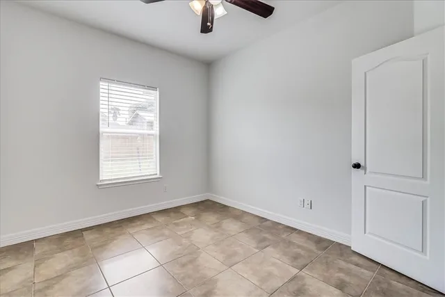 an empty room with chandelier fan and windows