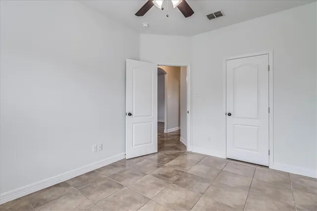 an empty room with closet and a chandelier fan