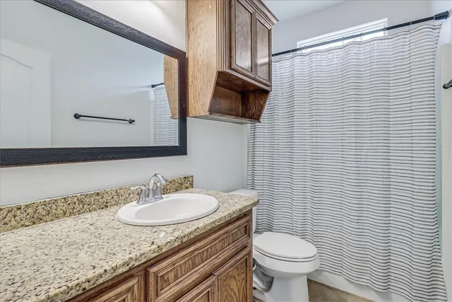 a bathroom with a granite countertop toilet sink and mirror