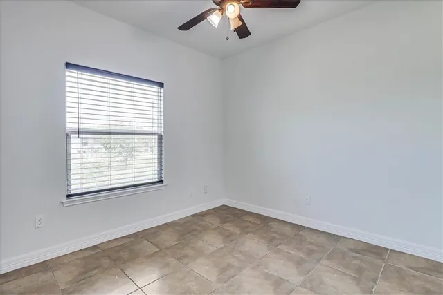 an empty room with a chandelier fan and windows