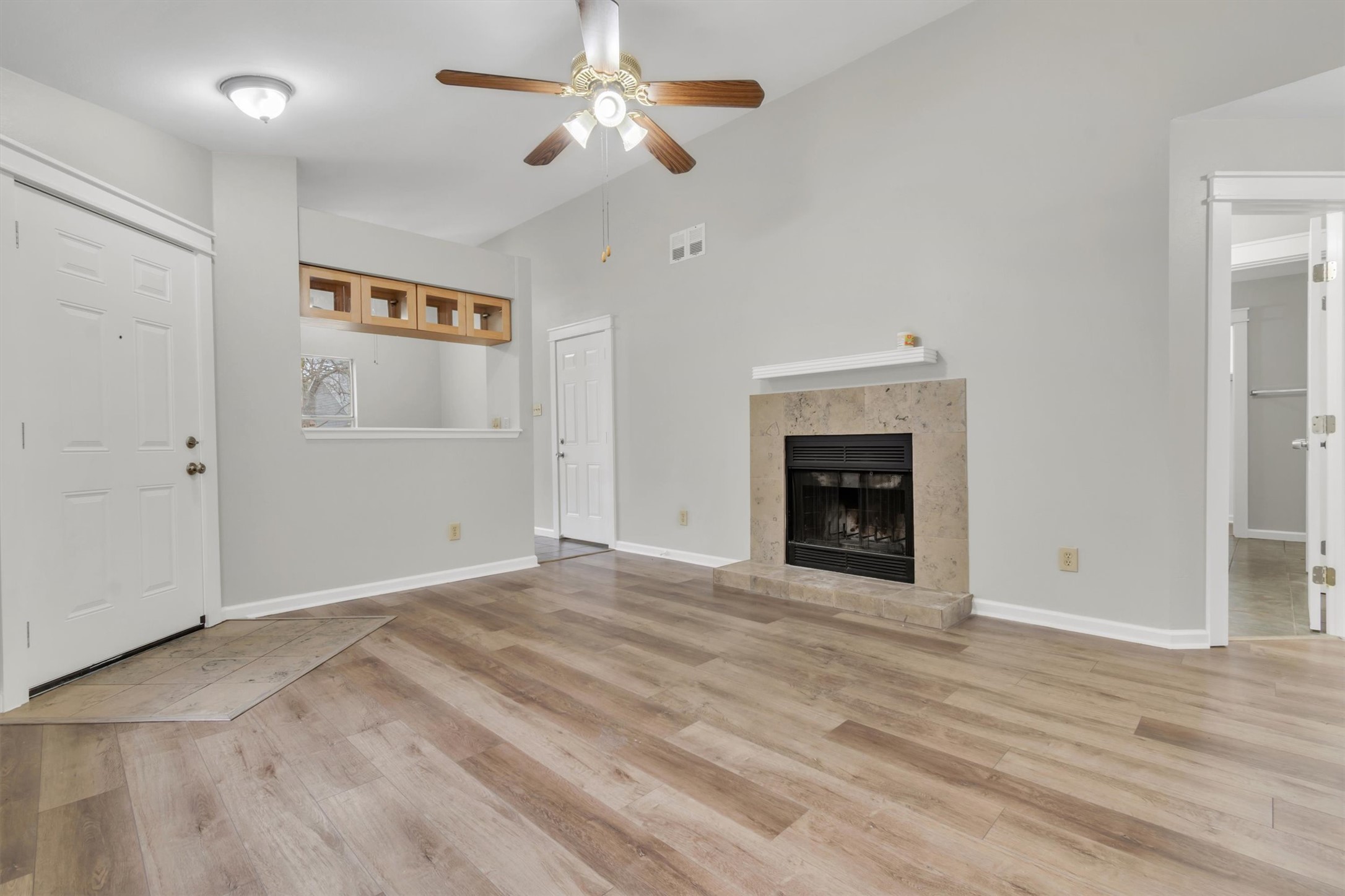 720 Decker Prairie Drive Austin, TX 78748 - Photo 4 of 21 Unfurnished living room featuring lofted ceiling, a ceiling fan, a fireplace, and light wood-type flooring