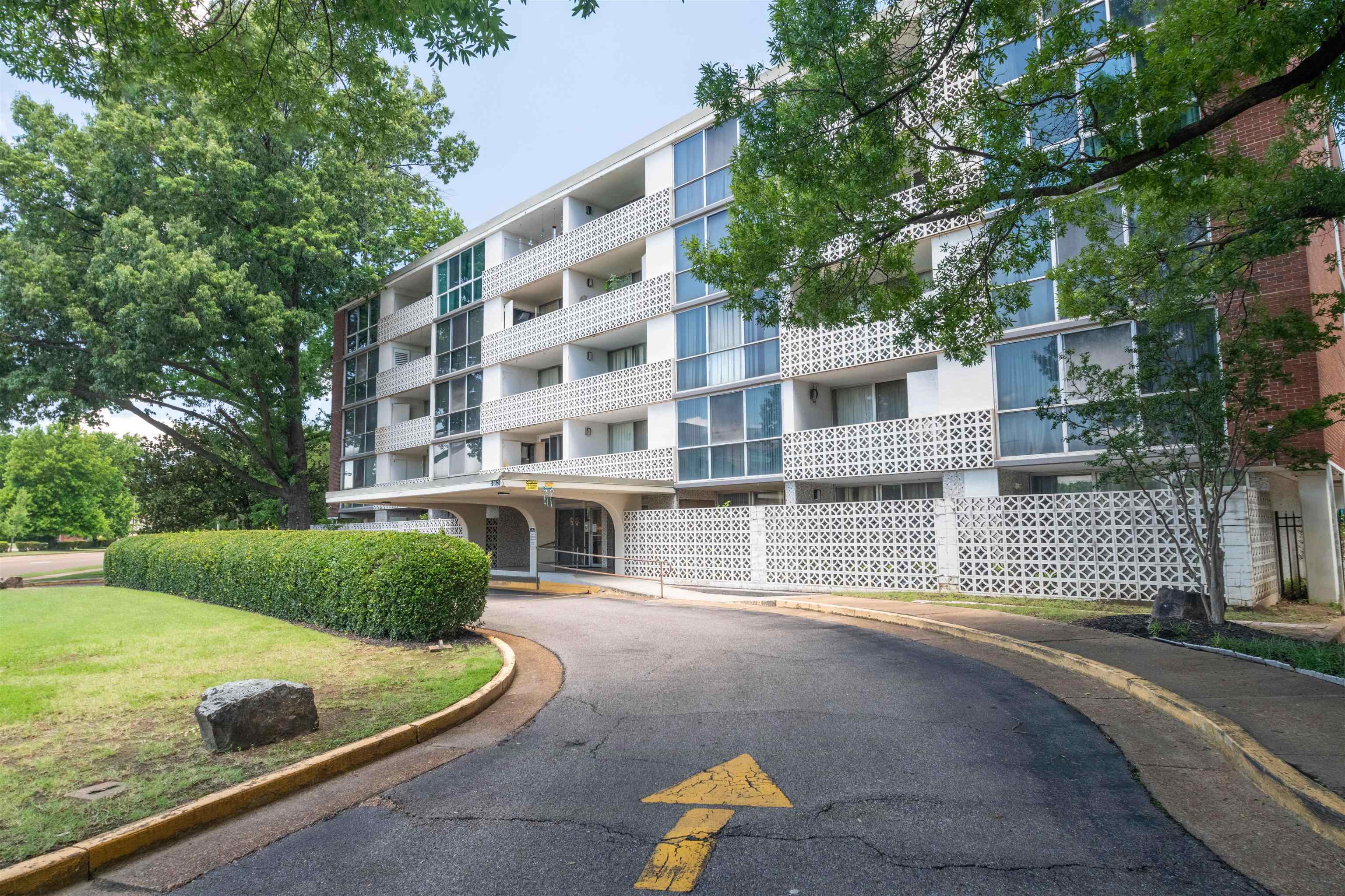 Multistory building with a covered drive-through entry, extensive window lines, and decorative white screen block elements