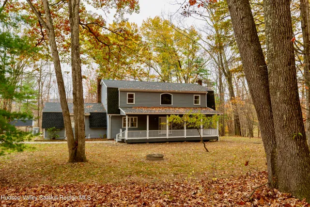 a front view of a house with a large tree