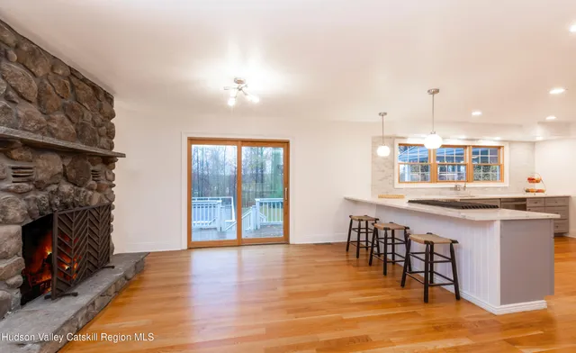 a kitchen with stainless steel appliances granite countertop a stove top oven a sink a dining table and chairs with wooden floor