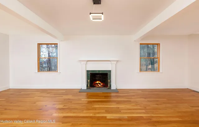 a view of a livingroom with a fireplace wooden floor and windows