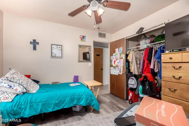 a bedroom with a bed a flat screen tv and a ceiling fan