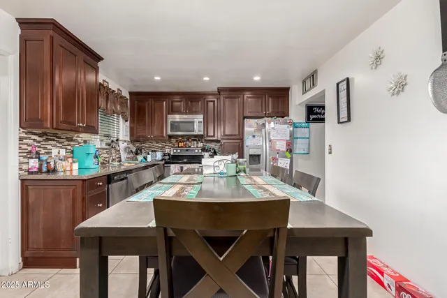 a kitchen with stainless steel appliances kitchen island granite countertop a table chairs microwave and sink