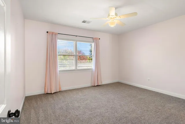 a view of empty room with window and ceiling fan