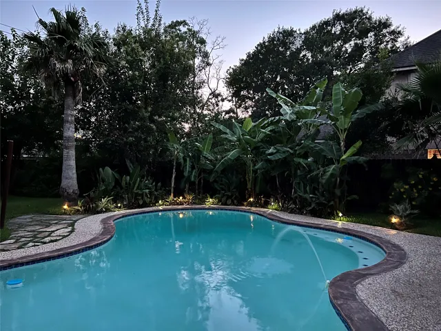 a view of a swimming pool with lawn chairs under an umbrella