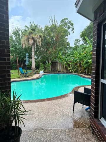 a view of a swimming pool with a patio and a yard