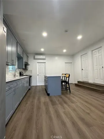 a kitchen with stainless steel appliances granite countertop a stove a sink a refrigerator and white cabinets with wooden floor