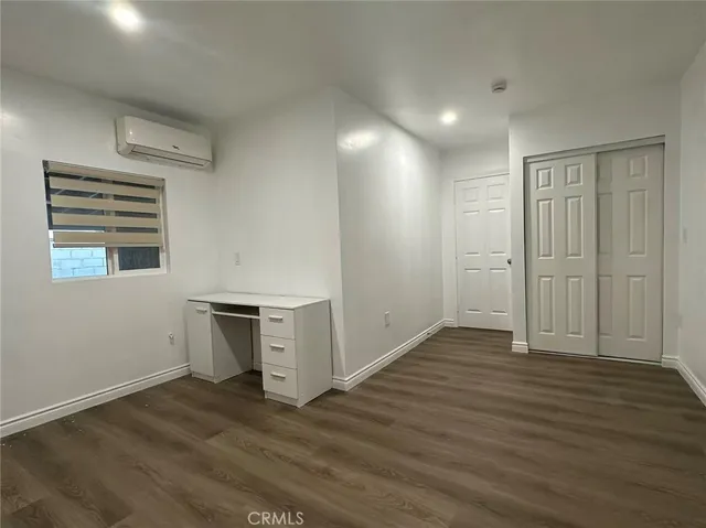 an empty room with wooden floor cabinet and windows