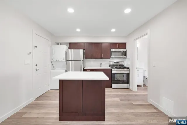 a kitchen with stainless steel appliances a refrigerator stove a sink and a oven with wooden floor