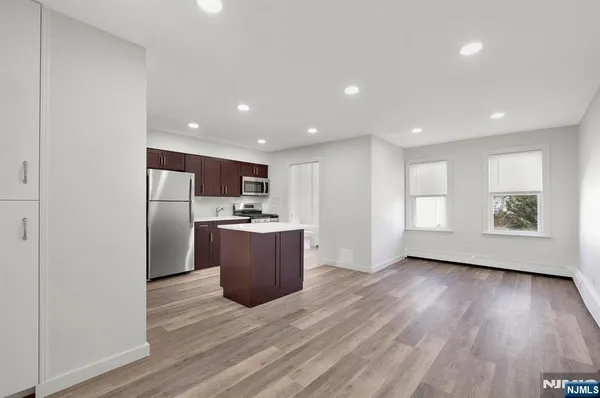 a view of kitchen with stainless steel appliances granite countertop a stove a refrigerator a sink and a microwave with wooden floor