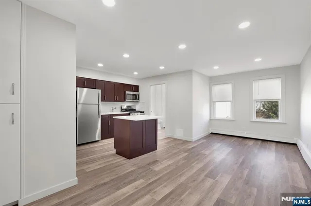 a view of kitchen with stainless steel appliances granite countertop a stove a refrigerator a sink and a microwave with wooden floor