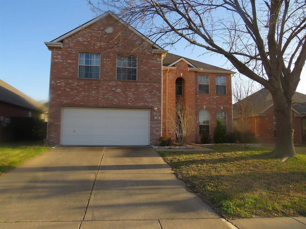 Traditional-style house featuring brick siding, a front yard, an attached garage, and driveway