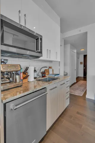 a kitchen with granite countertop stainless steel appliances a sink and cabinets