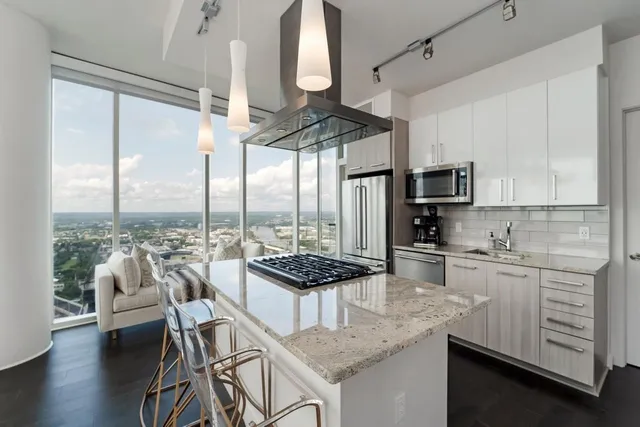 a kitchen with kitchen island granite countertop a stove a sink a dining table and chairs with wooden floor