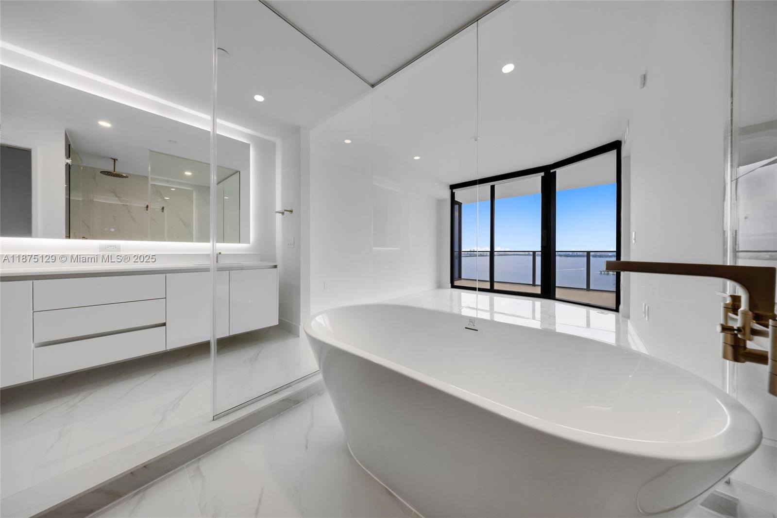 700 Northeast 24th Street, Unit 1706 Miami, FL 33137 - Photo 30 of 95 a large white kitchen with kitchen island a sink a stove and a large window