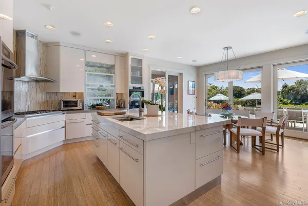 a large kitchen with kitchen island a large counter space a sink a stove and a large window