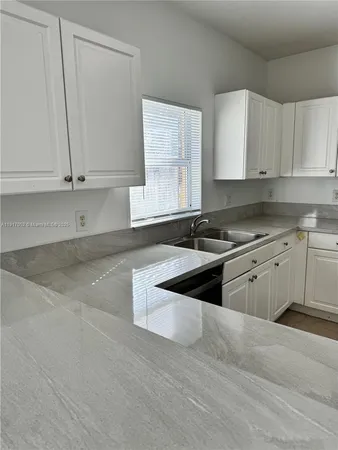 a kitchen with granite countertop white cabinets and white appliances