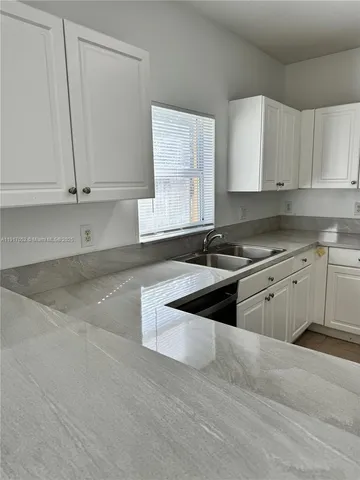a kitchen with granite countertop white cabinets and white appliances