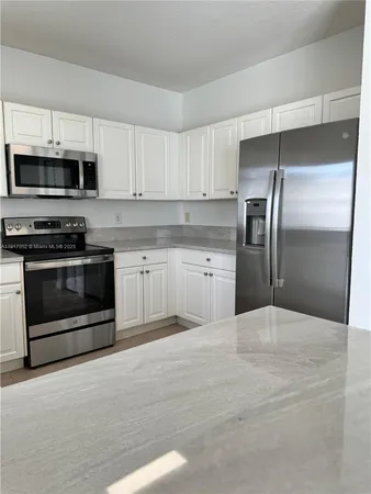 a kitchen with stainless steel appliances granite countertop a stove a refrigerator and a microwave