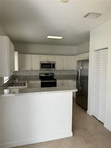 a kitchen with stainless steel appliances granite countertop a refrigerator a stove and a sink