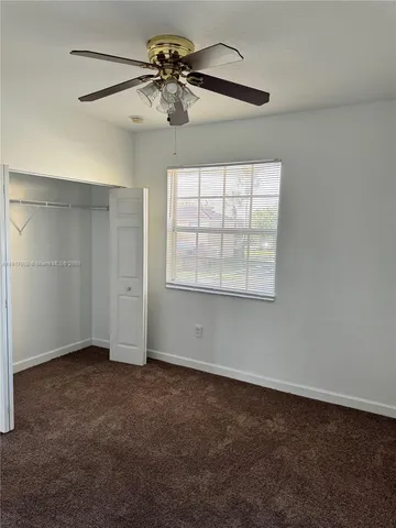 an empty room with a window and a ceiling fan