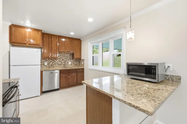 a kitchen with stainless steel appliances granite countertop a stove a microwave a sink and a refrigerator