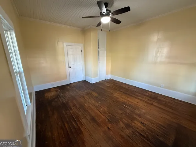 a view of empty room with wooden floor and fan