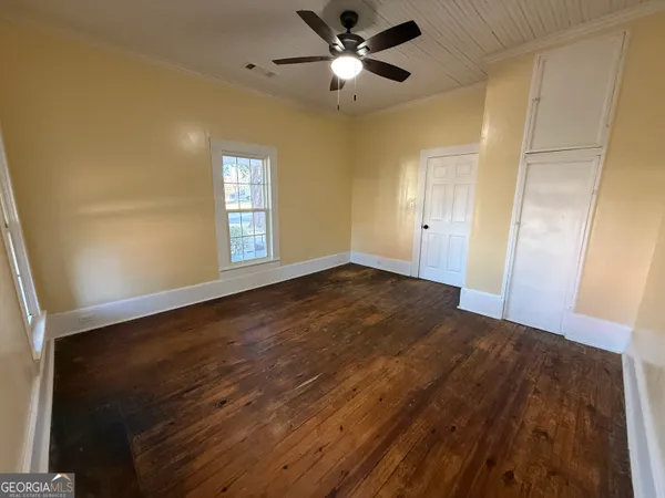 an empty room with wooden floor fan and windows