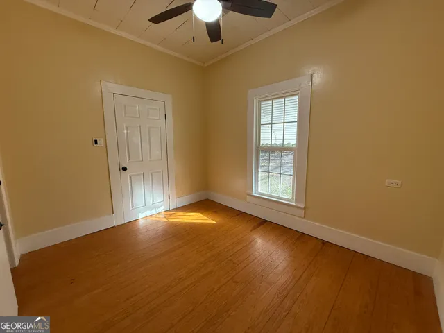 a view of empty room with wooden floor and fan