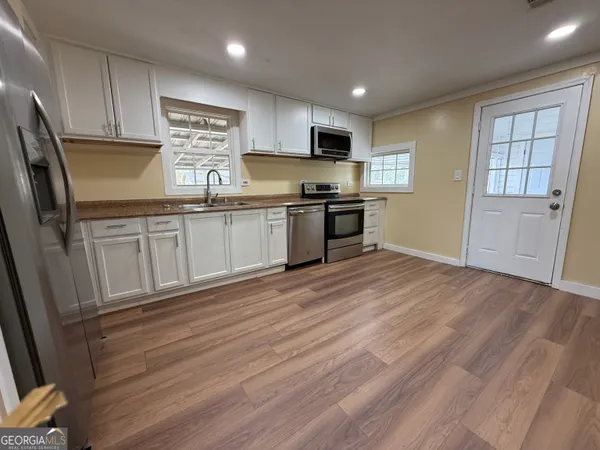 a kitchen with stainless steel appliances granite countertop a refrigerator a stove top oven a sink dishwasher and wooden floor