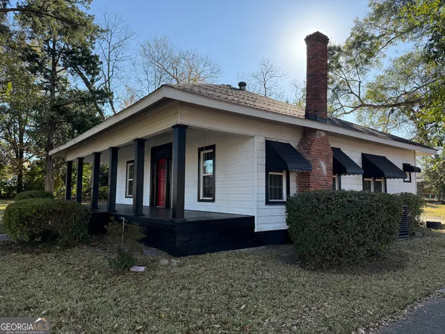a view of a house with a yard and large tree