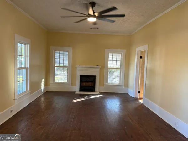a view of an empty room with window and wooden floor