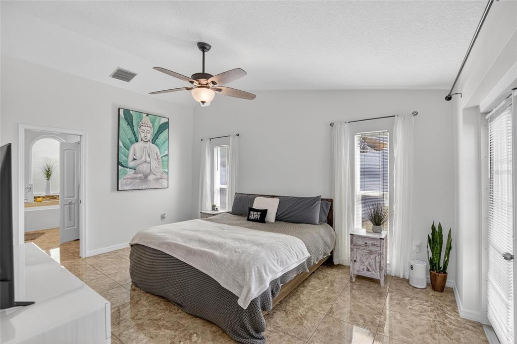 1668 Allens Ridge Drive North Palm Harbor, FL 34683 - Photo 18 of 48 a bedroom with a large bed chandelier and a window