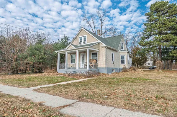 a front view of a house with a garden and trees