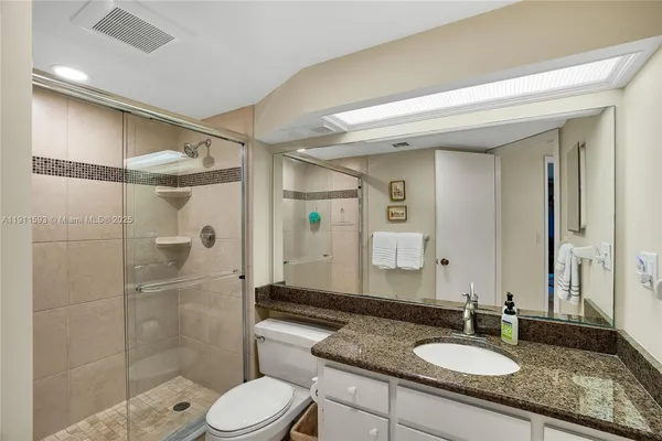 a bathroom with a shower sink vanity mirror and toilet