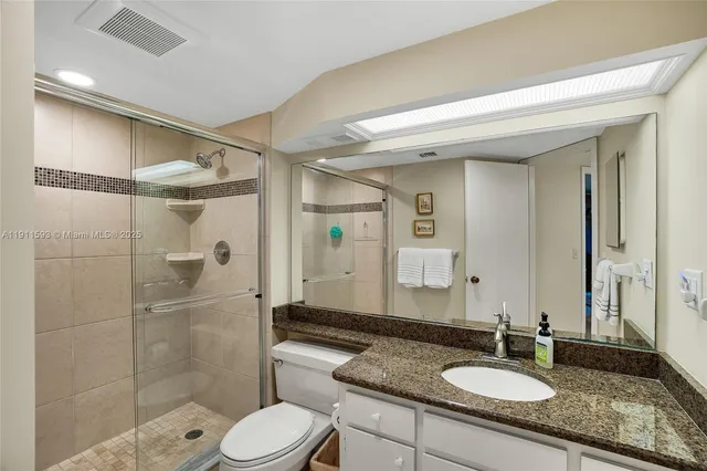 a bathroom with a shower sink vanity mirror and toilet