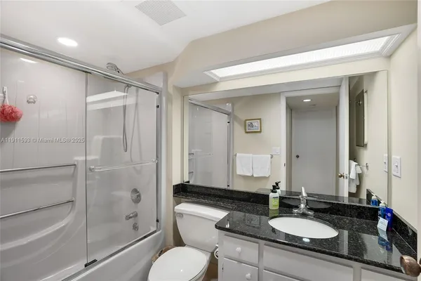 a bathroom with a granite countertop sink toilet a mirror and shower