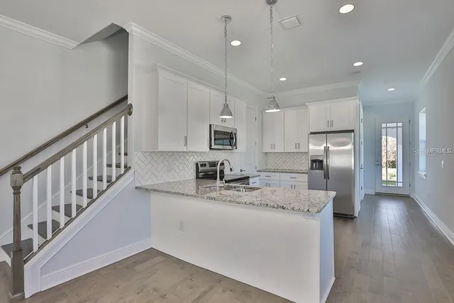 a kitchen with stainless steel appliances granite countertop a sink refrigerator and cabinets